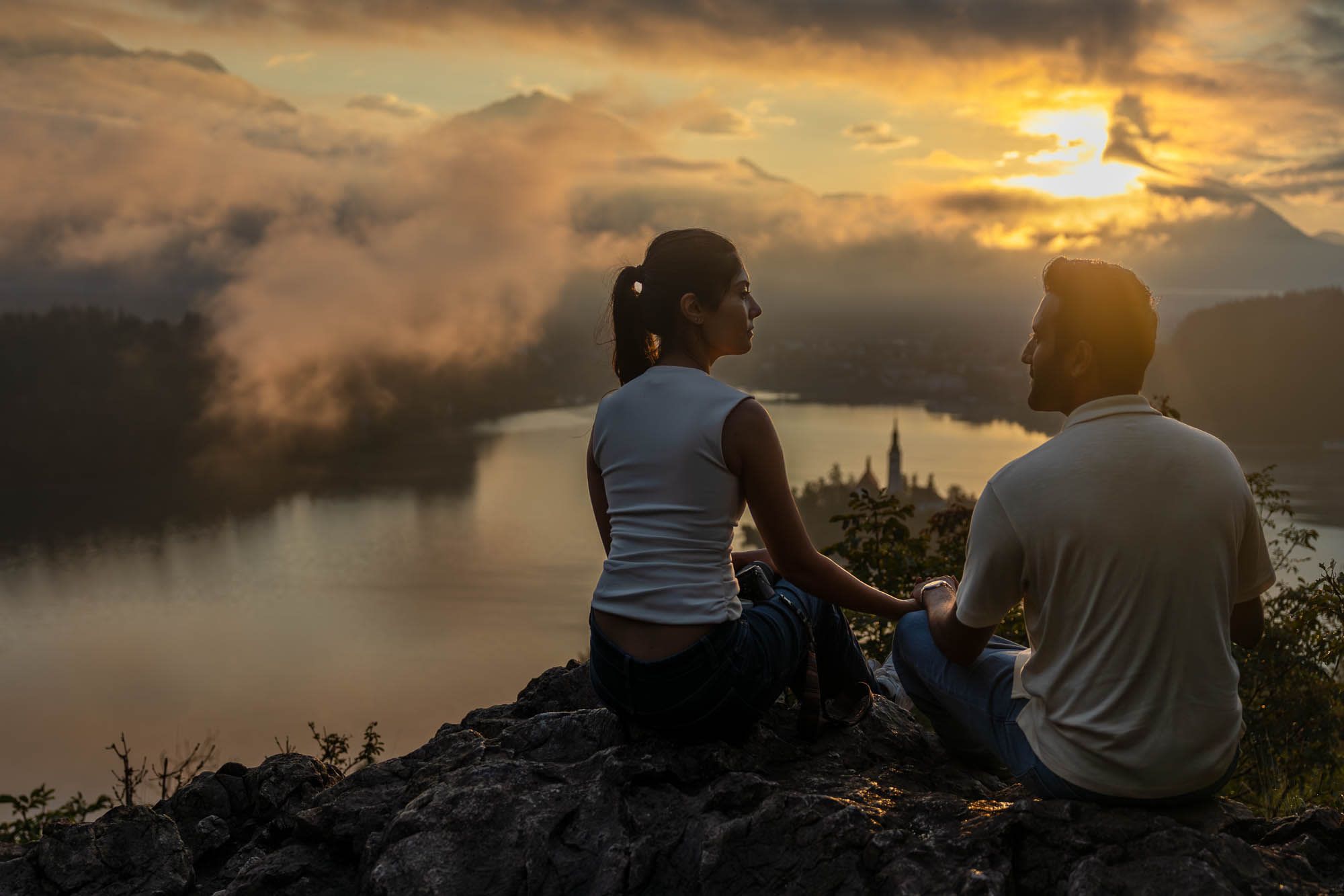 Romantic sunrise photo of a couple at Ojstrica viewpoint, overlooking Lake Bled and its iconic island church.