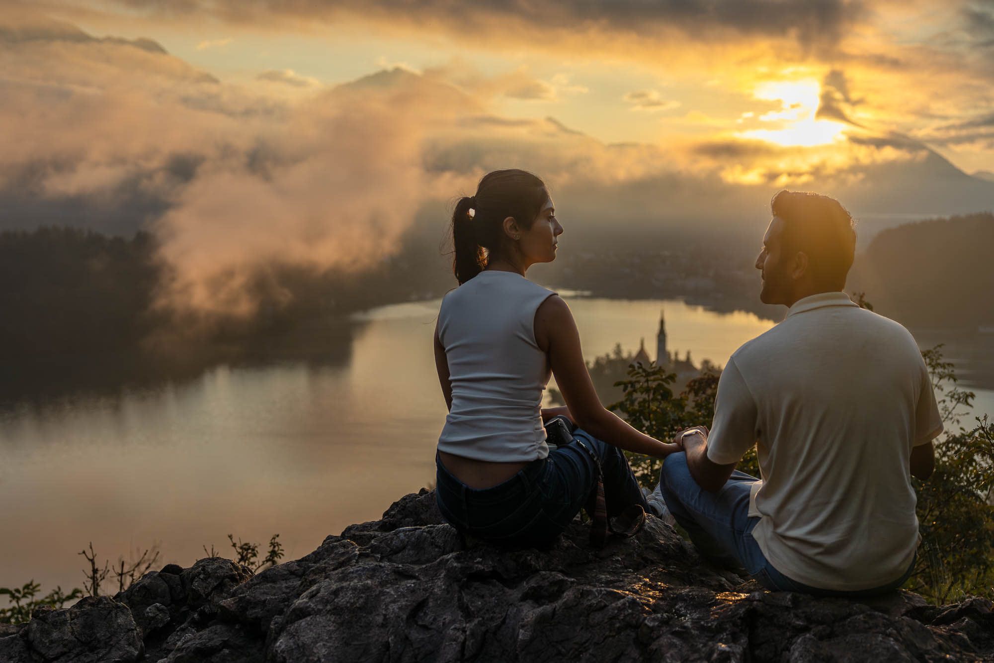 Romantic sunrise photo of a couple at Ojstrica viewpoint, overlooking Lake Bled and its iconic island church.