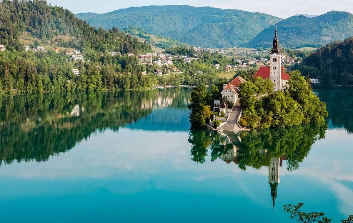 A scenic view of Lake Bled showcasing the island with its iconic church surrounded by calm waters and lush greenery.