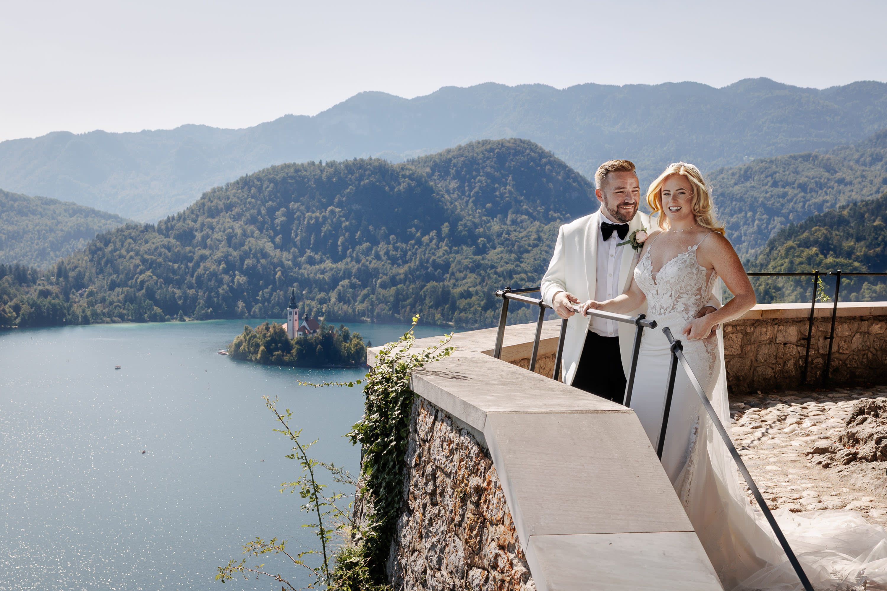 Bride and groom at Bled Castle with Lake Bled island view.