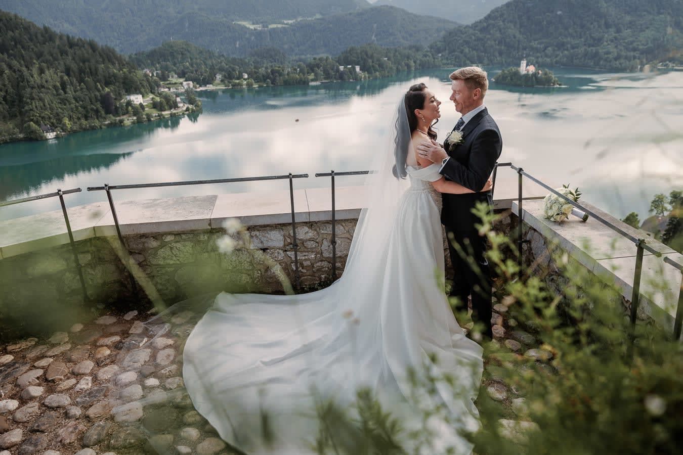 Bride and groom sharing an intimate moment at Bled Castle overlooking Lake Bled and the island church.