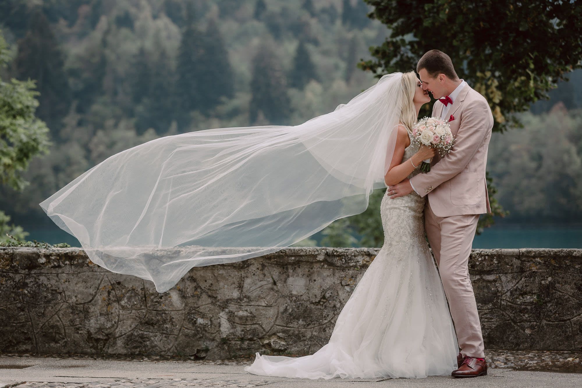 Bride and groom kissing with a flowing veil during a wedding portrait on Bled Island, Lake Bled, Slovenia.