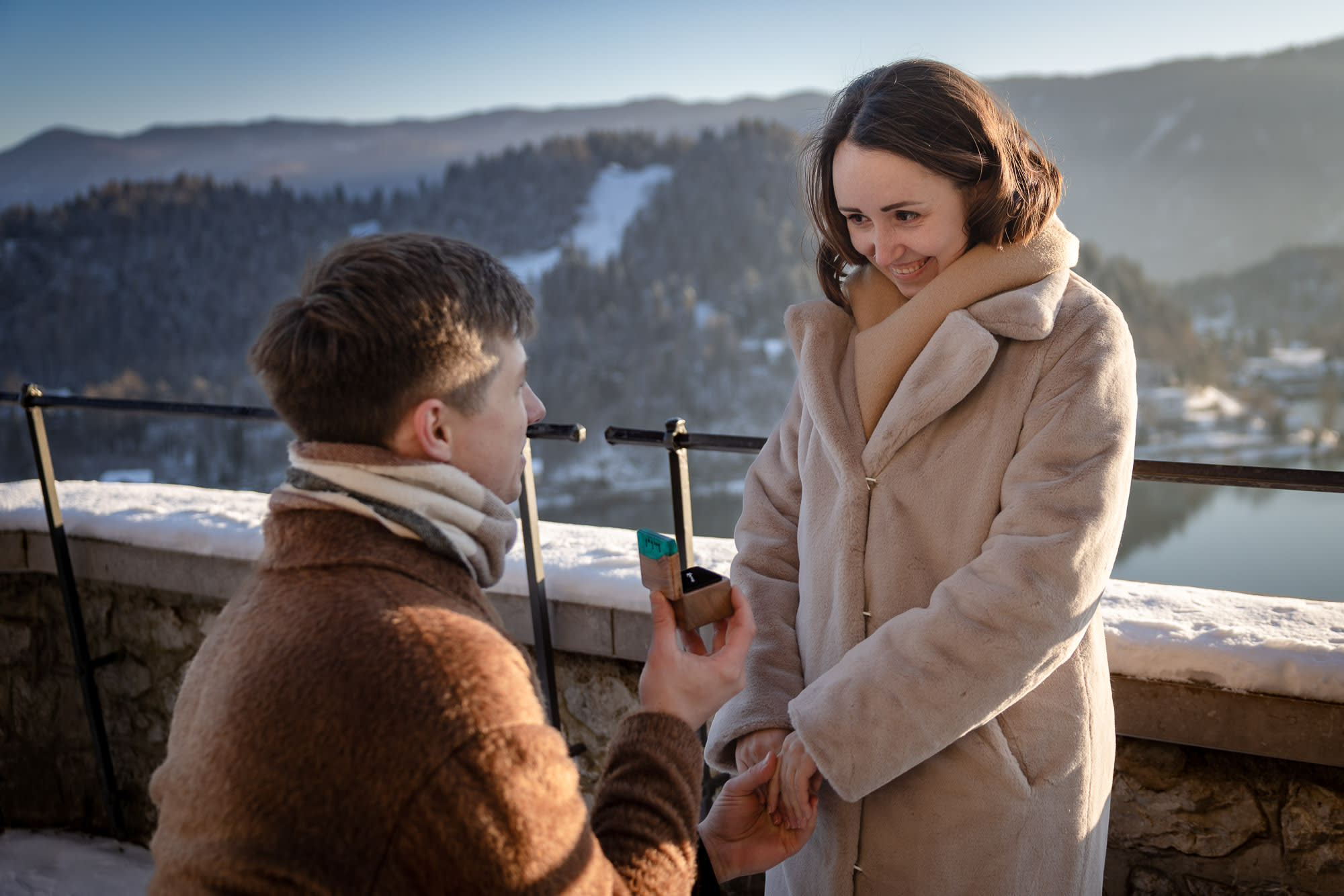 Winter proposal on a snowy terrace overlooking Lake Bled.
