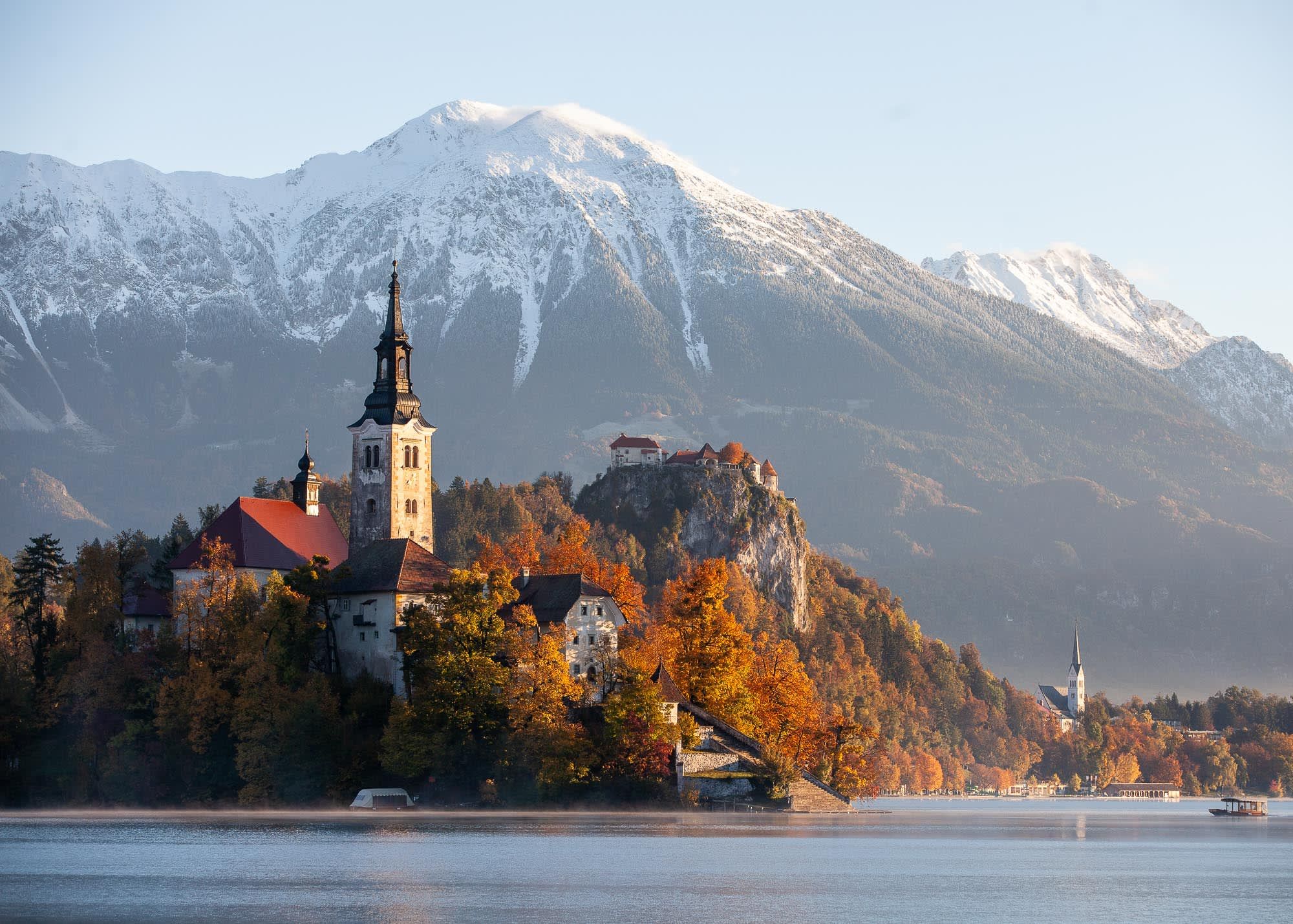 Bled island and Bled castle in autumn, in the backrgound there is early snow on the mountains.