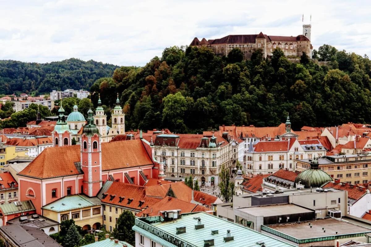 A view of the historic Ljubljana Castle perched on a hill, surrounded by the charming rooftops of Ljubljana's old town.