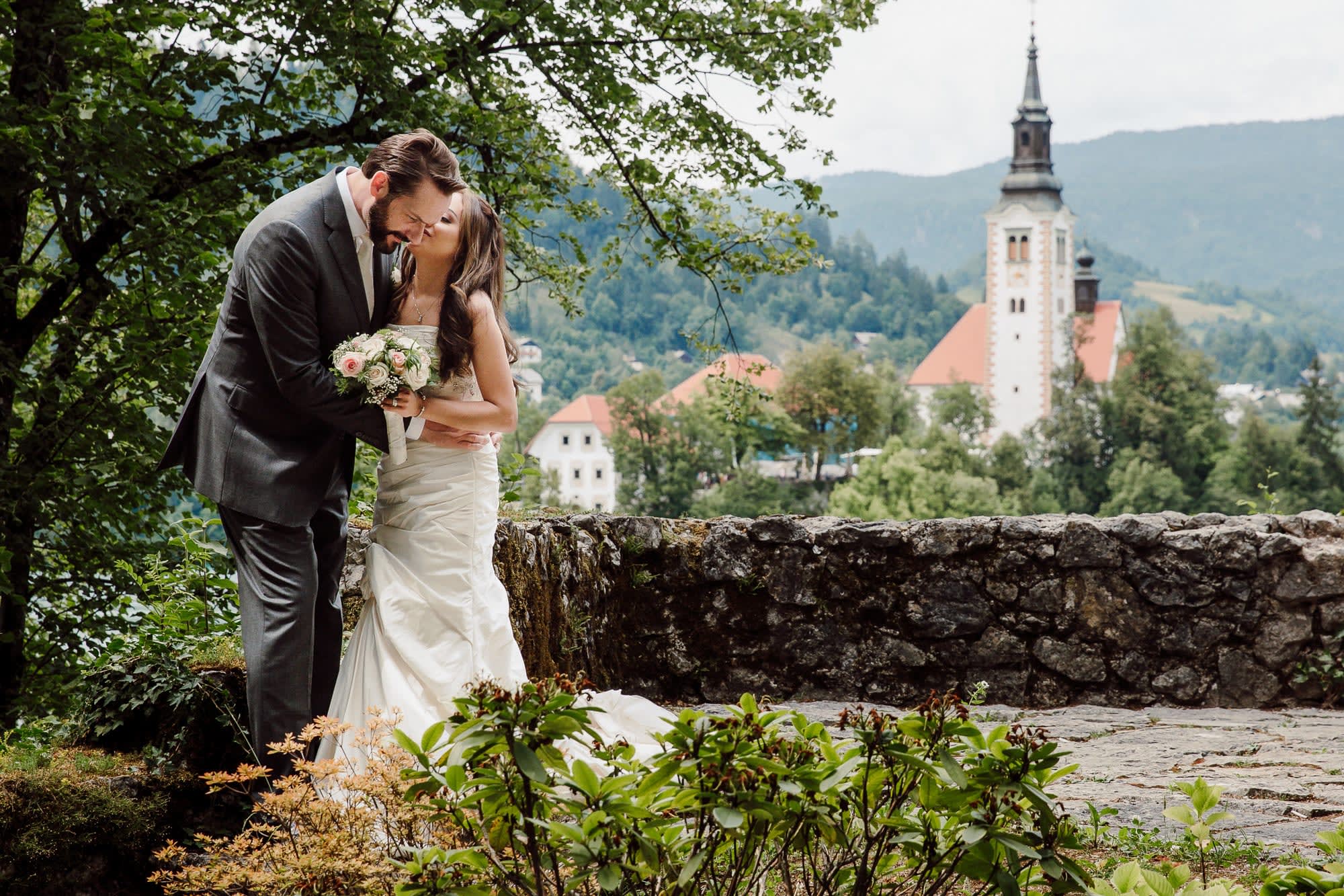 A couple sharing a gentle kiss surrounded by greenery during an intimate Lake Bled elopement portrait session.