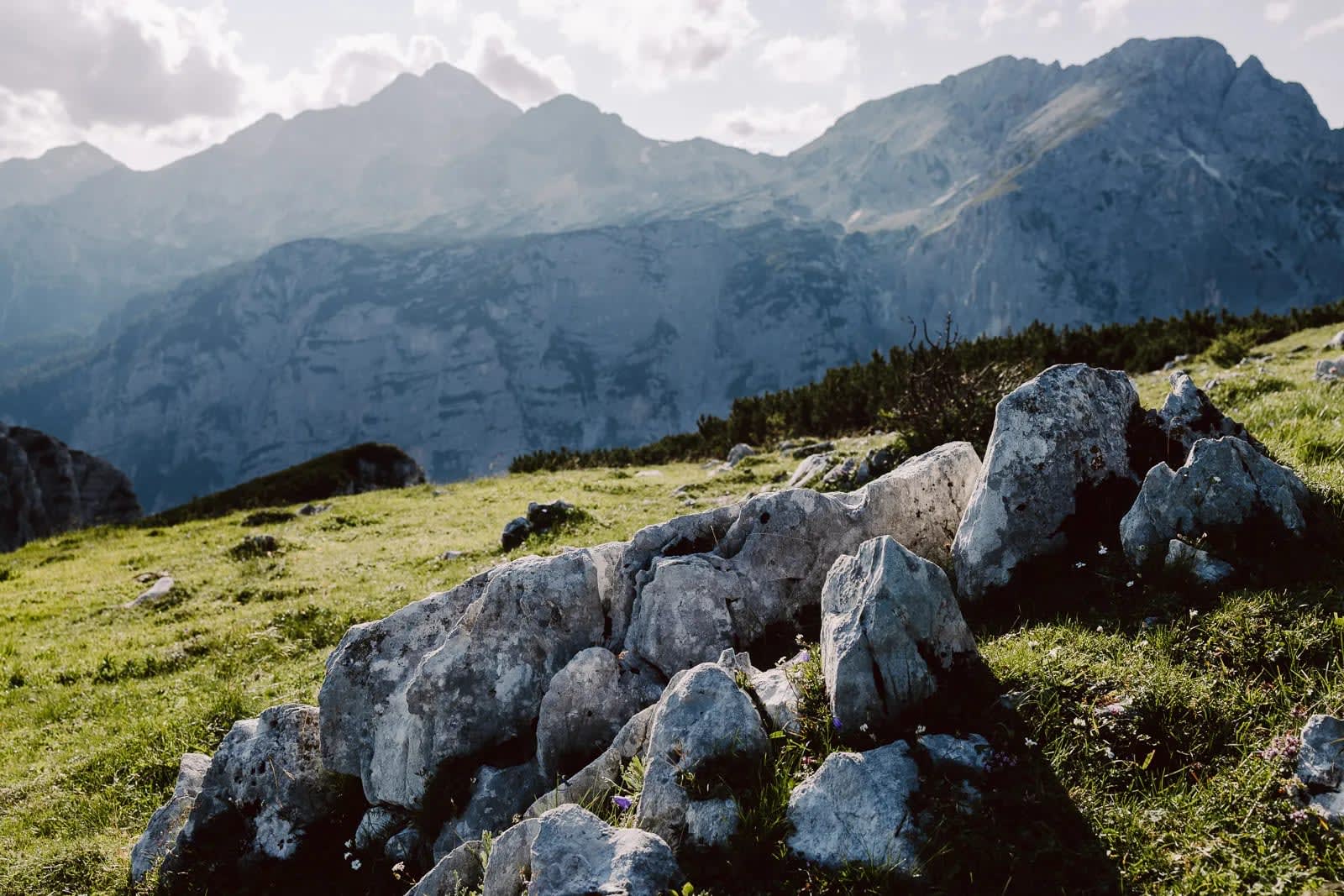 A picturesque view of rocky terrain with a backdrop of towering mountains under a partly cloudy sky.