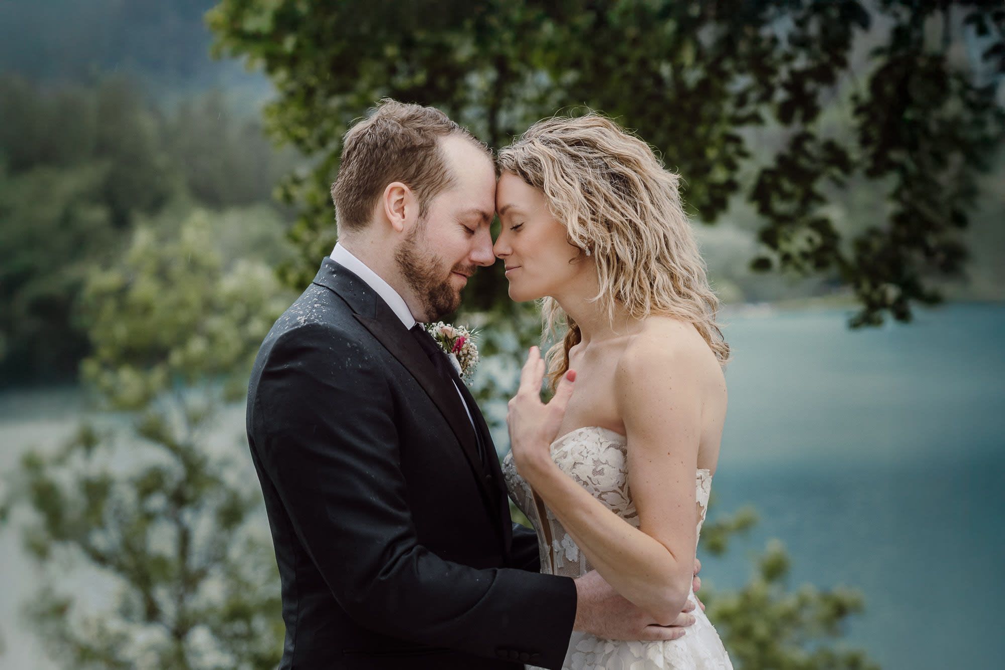 Bride and groom sharing an intimate moment in light rain by Lake Bled, Slovenia.