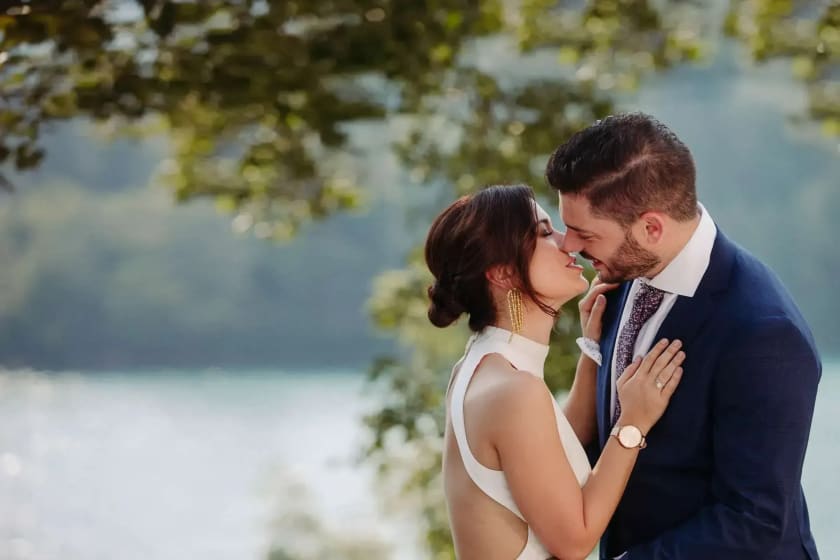 Bride and groom sharing a romantic kiss under the trees on Bled island, captured in elegant wedding photography.