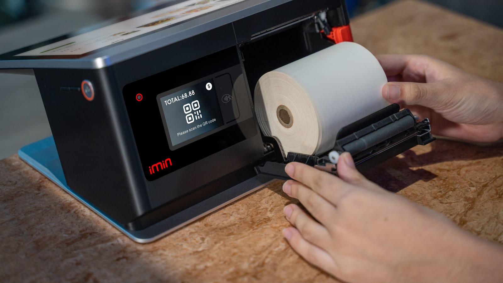 Hands loading a new roll of thermal paper into a receipt printer