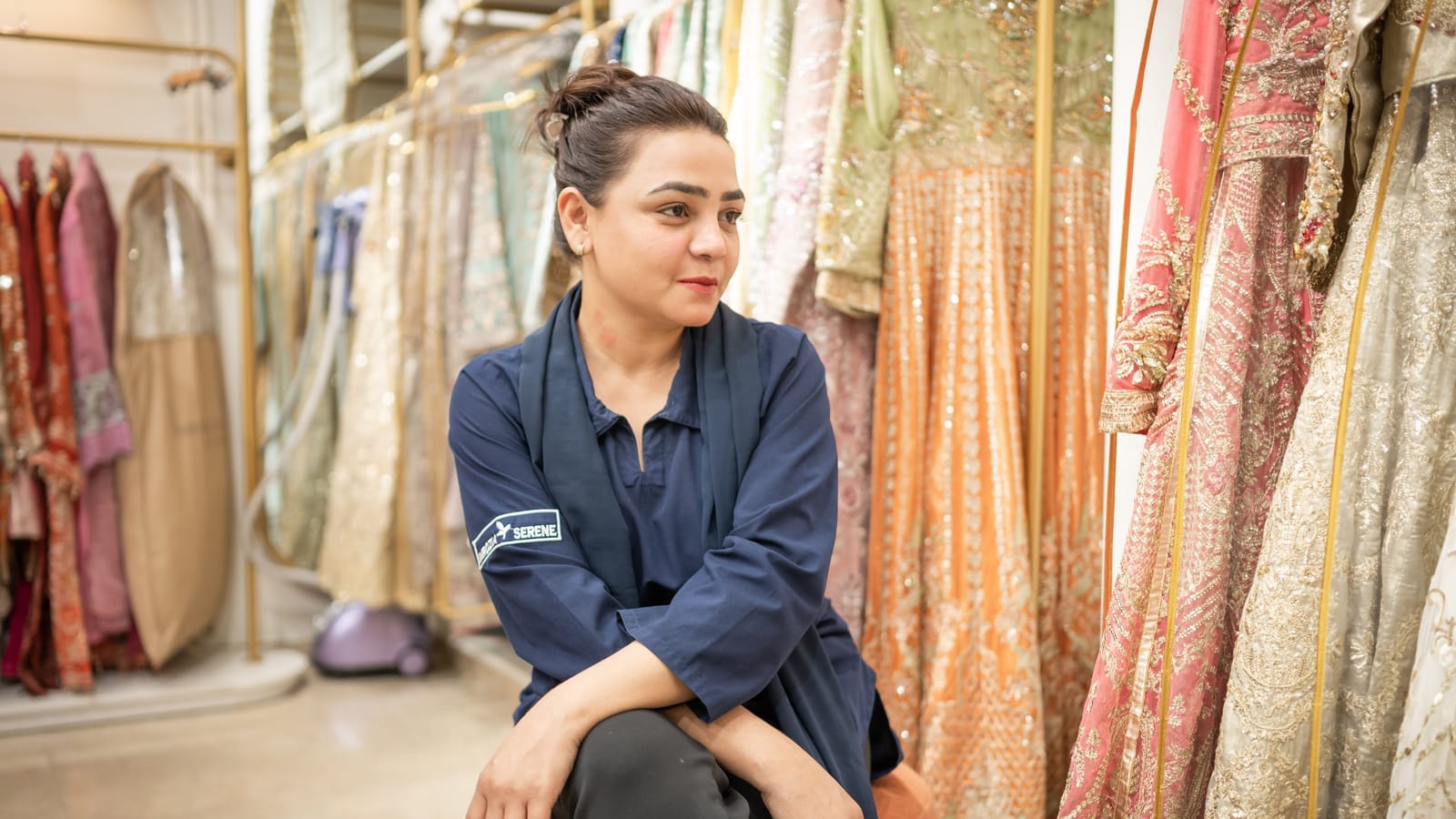 A shop assistant in a clothing boutique in Islamabad, surrounded by dresses on racks