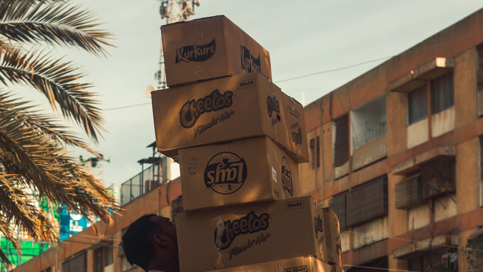 A man carrying a stack of parcels through a busy street in Karachi