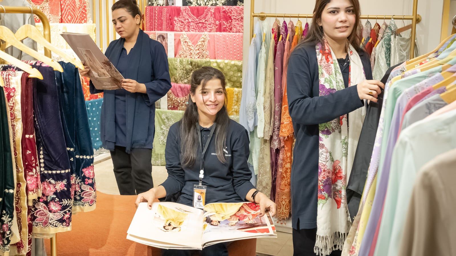Shoppers looking at fabrics with a sales assistant in a clothing store in Islamabad