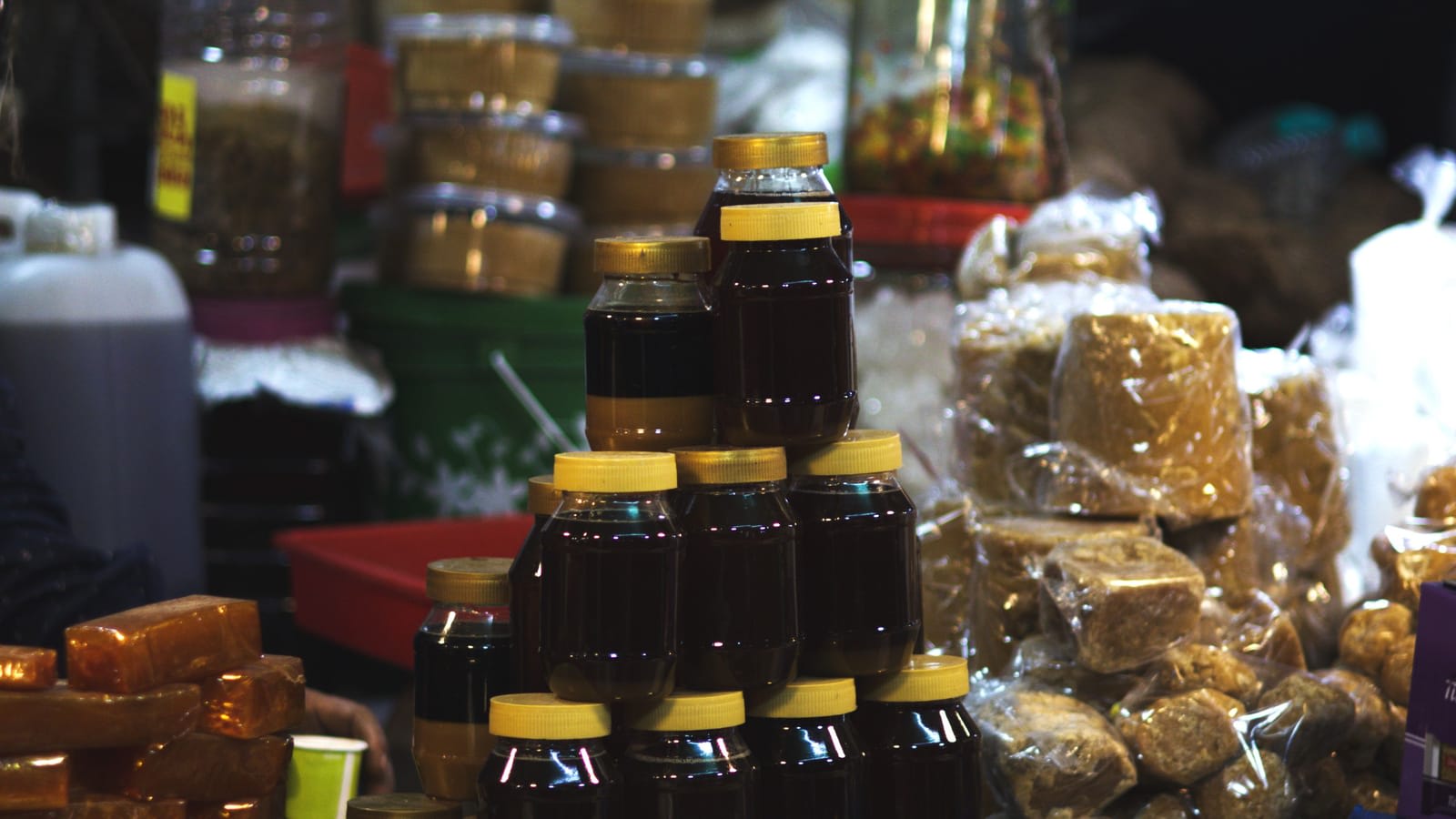 Jars of honey, loose sweets and packed goods at a market stall
