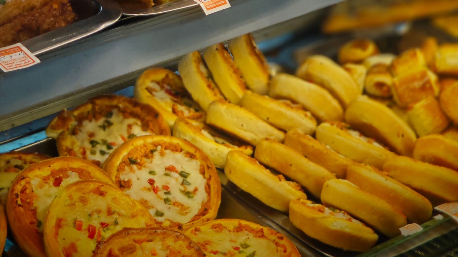 Pastries, buns and pizza slices in a bakery display case