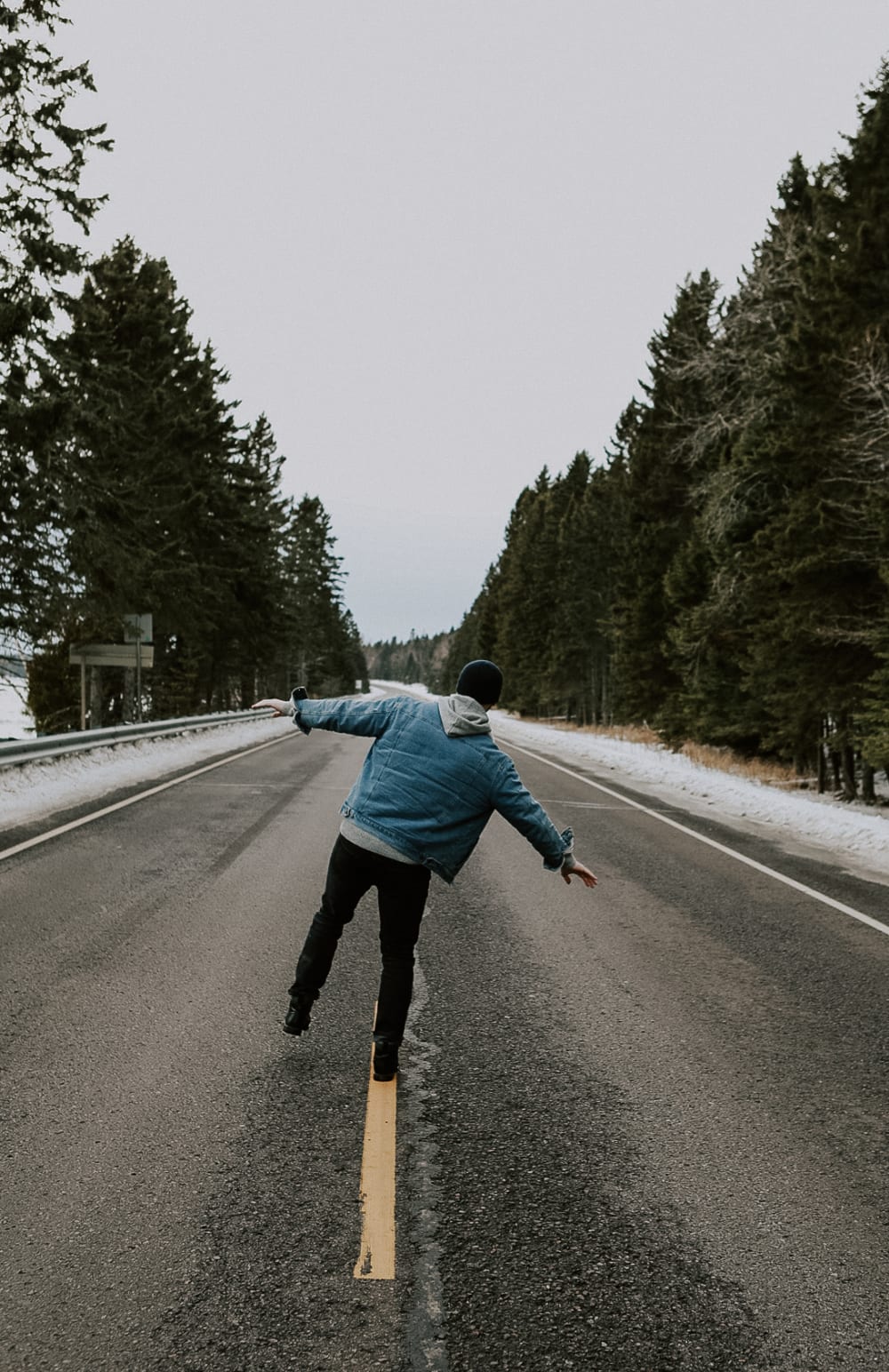 Josh Wicklund longboarding down an empty tree-lined North Shore road, arms out for balance