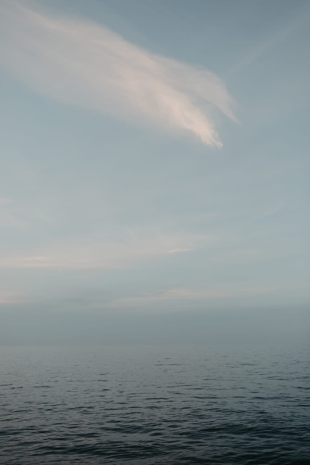 A minimal, calm expanse of Lake Superior with a single wisp of cloud