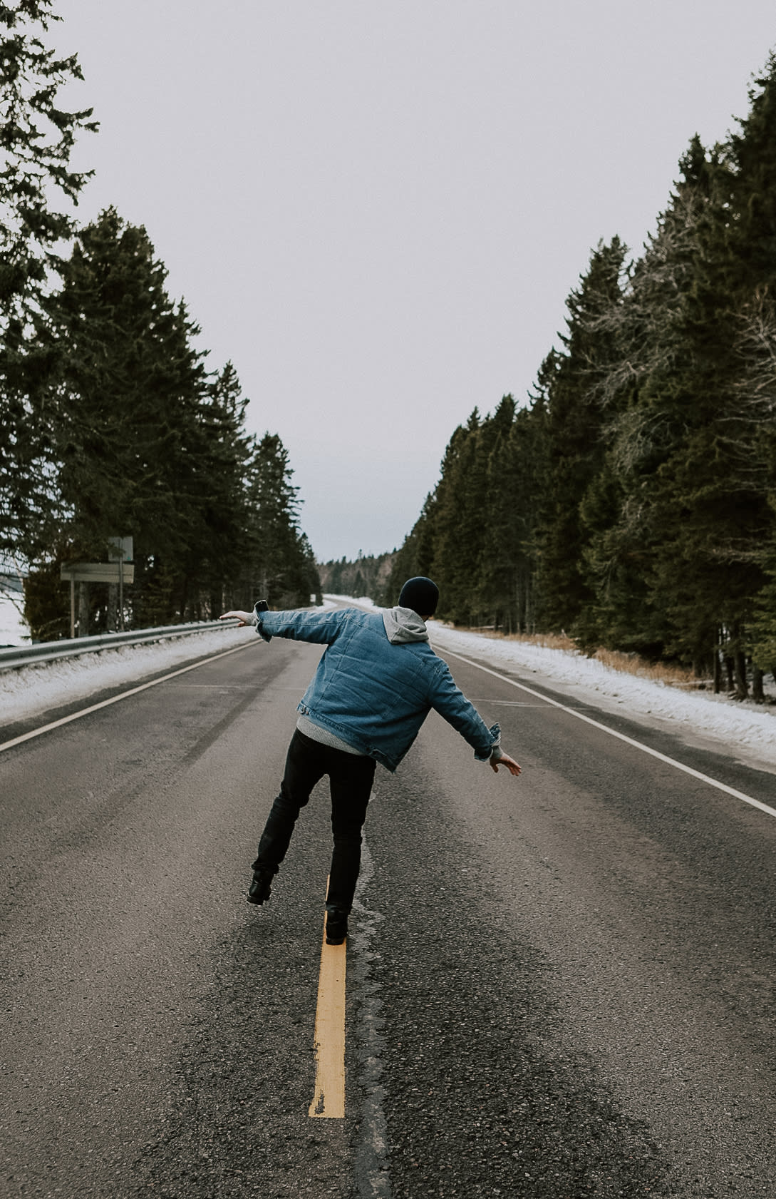 Josh Wicklund longboarding down an empty tree-lined North Shore road, arms out for balance