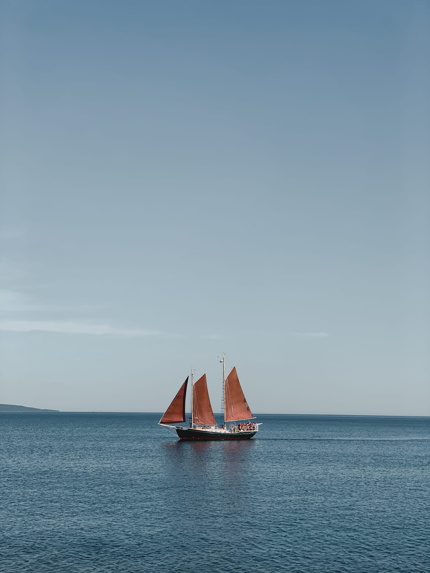 A tall-masted schooner sailing across a calm Lake Superior