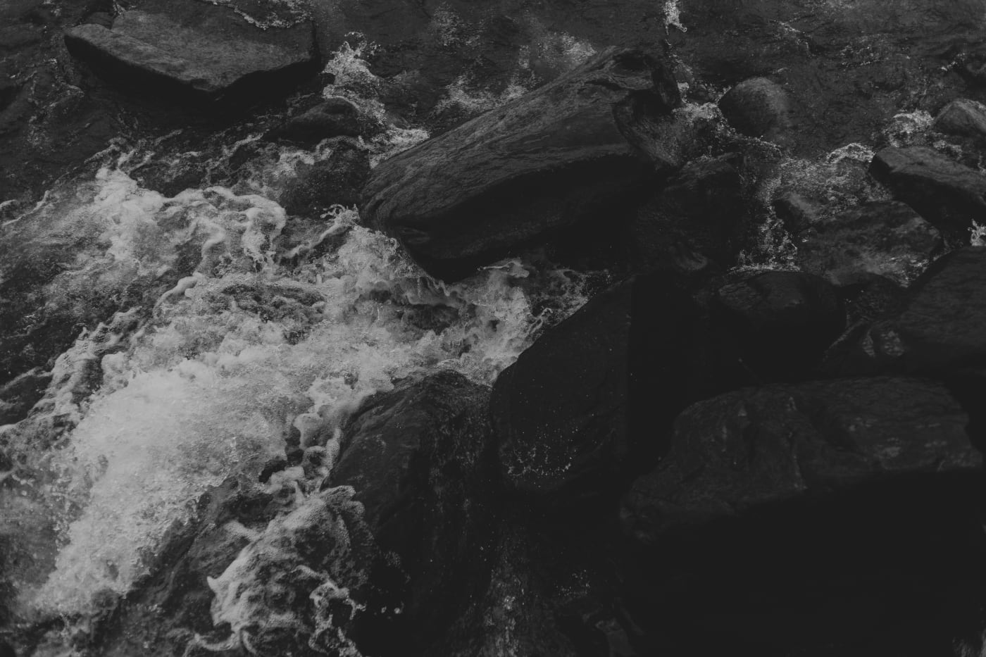 Black and white surf breaking over dark rock on the Lake Superior shore