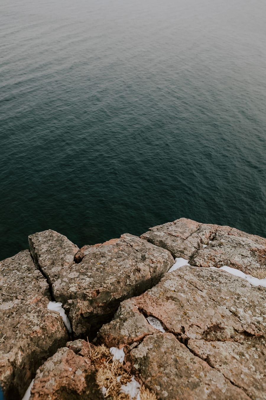 Clear teal Lake Superior water lapping against rock, seen from above