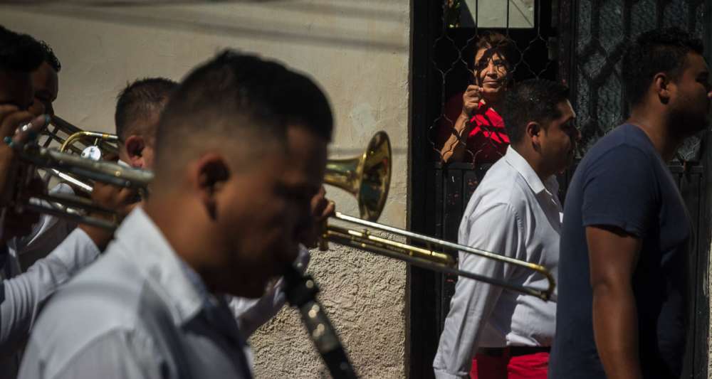 Woman watching a banda go by in a procession in Jalisco.