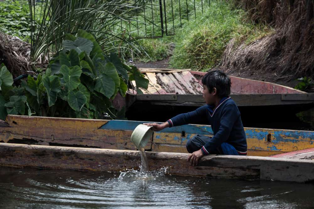 Boy emptying water from his boat at Xochimilco.