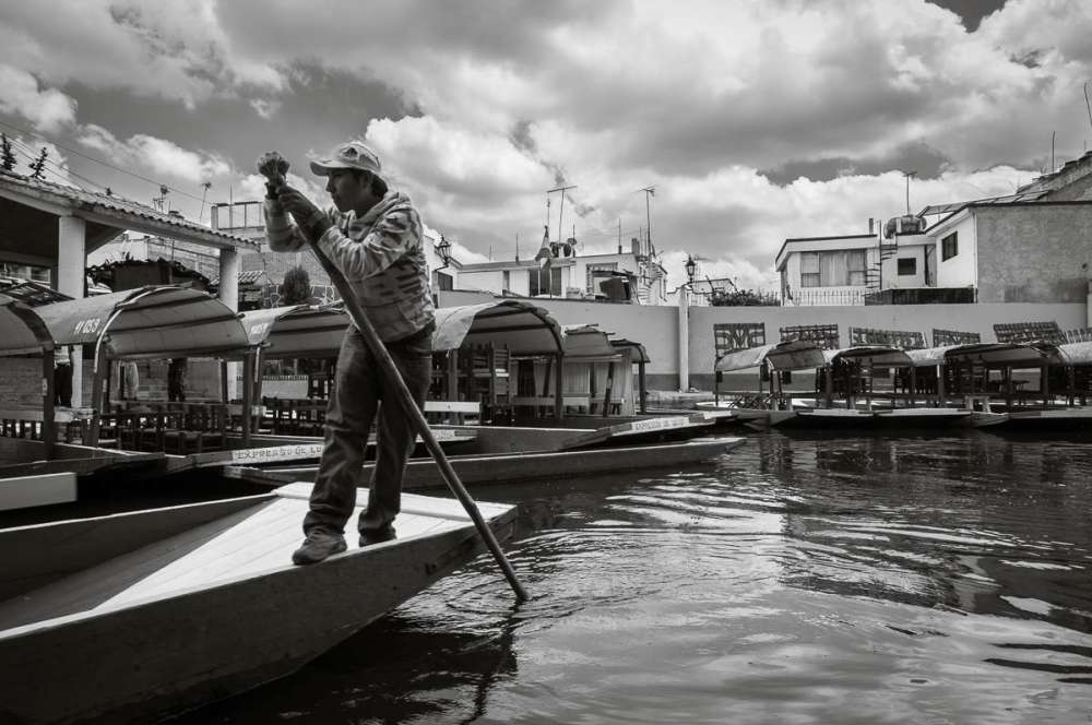 A trajinera operator pushing his boat with a pole at Xochimilco.