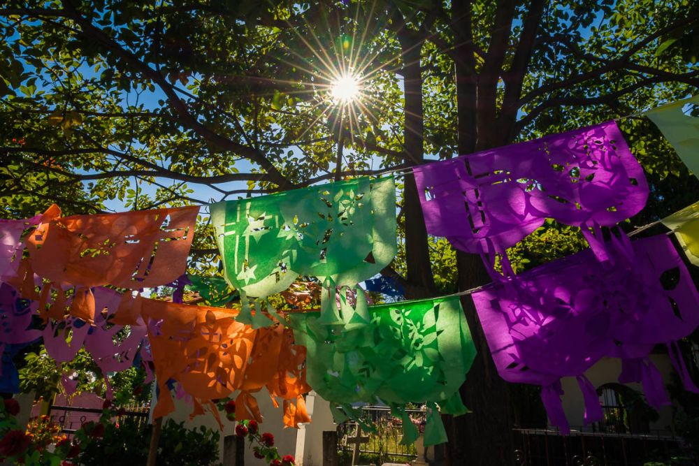 Hand-cut papel picado hangs above a grave in the Ajijic cemetery on the Day of the Dead.