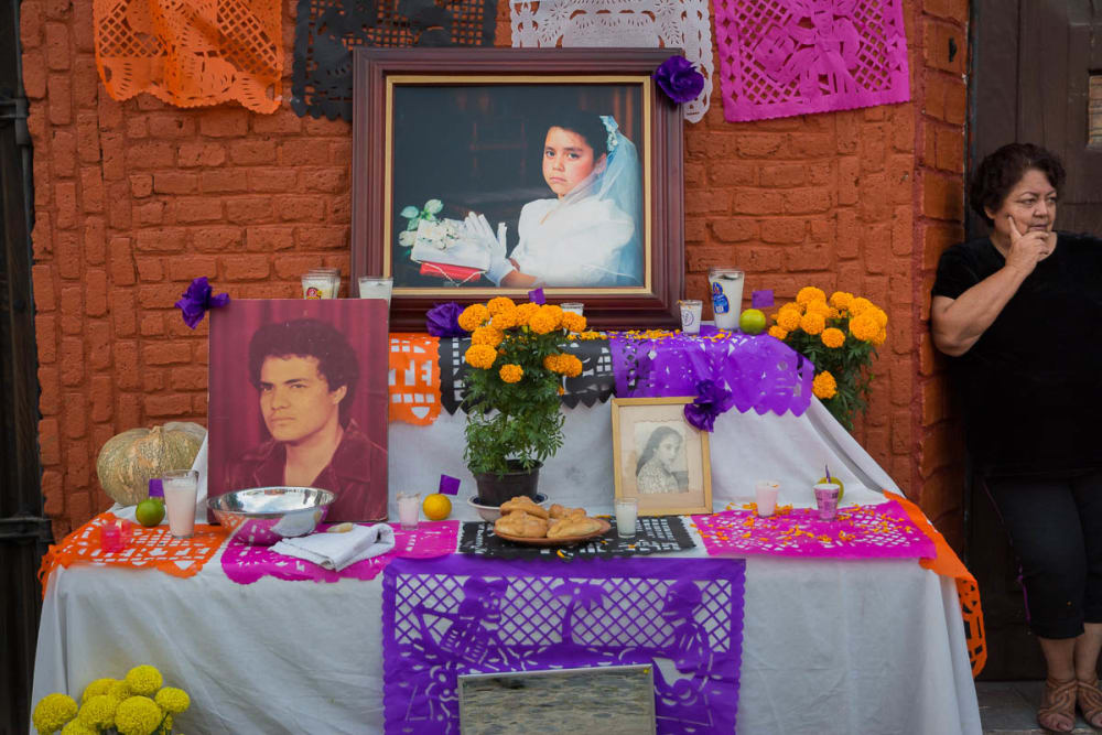 A woman next to a Día de los Muertos altar for her family.