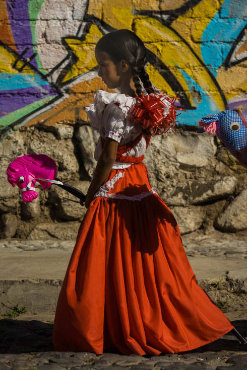 An adelita with a toy horse takes part in the Revolution Day parade in Ajijic, Jalisco, Mexico.