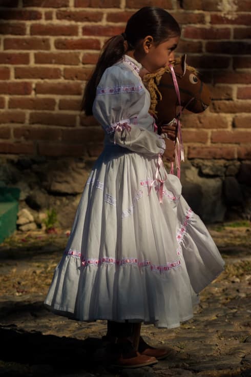 An adelita with a toy horse takes part in the Revolution Day parade in Ajijic, Jalisco, Mexico.