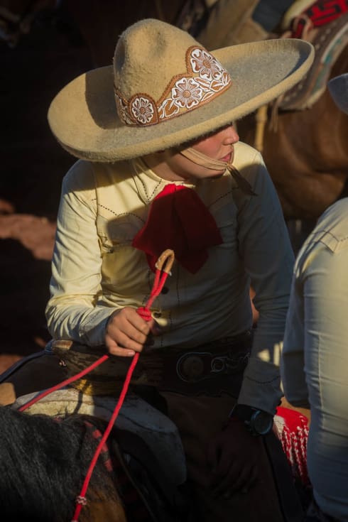 Young cowboy talking to other cowboys.