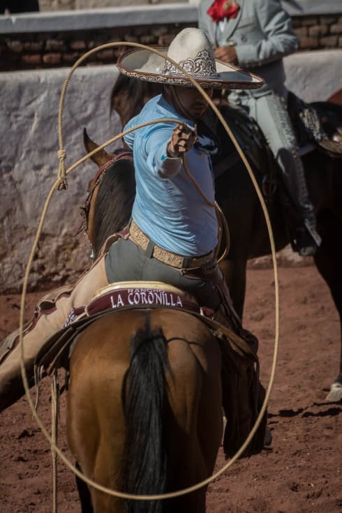 A charro throws a lasso during a charrería performance on the Day of the Cowboy in Ajijic.