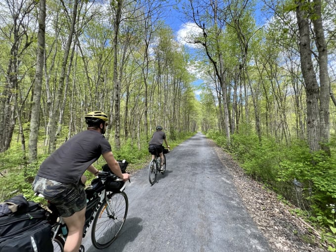 Lukas and Myles riding ahead on a gravel path lined with trees