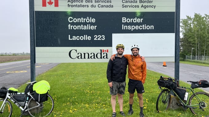 Lukas and Danny posing in front of the Canada border sign