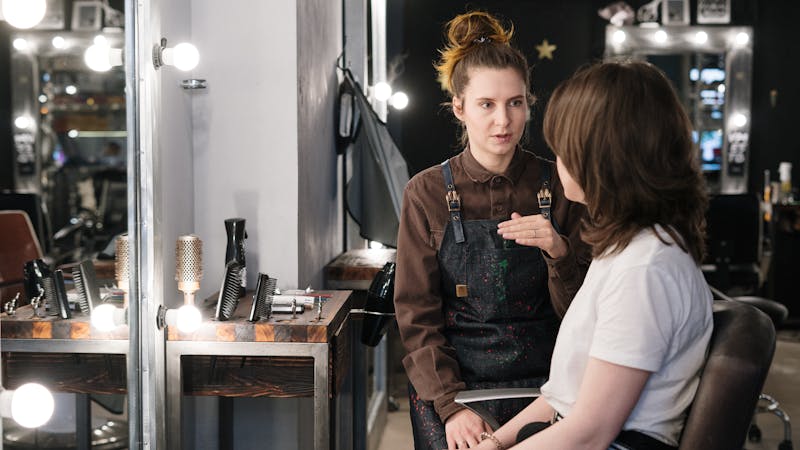 Professional hairstylist consulting with client about services in a DFW salon