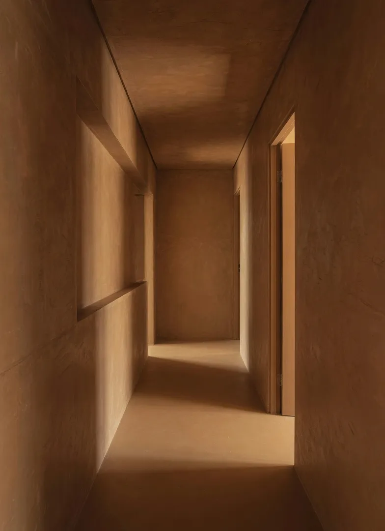 Narrow hallway transformed by seamless warm earthy ochre and brown color drenching, showing how going all in with one cohesive palette makes connecting spaces feel intentional and architecturally elegant.