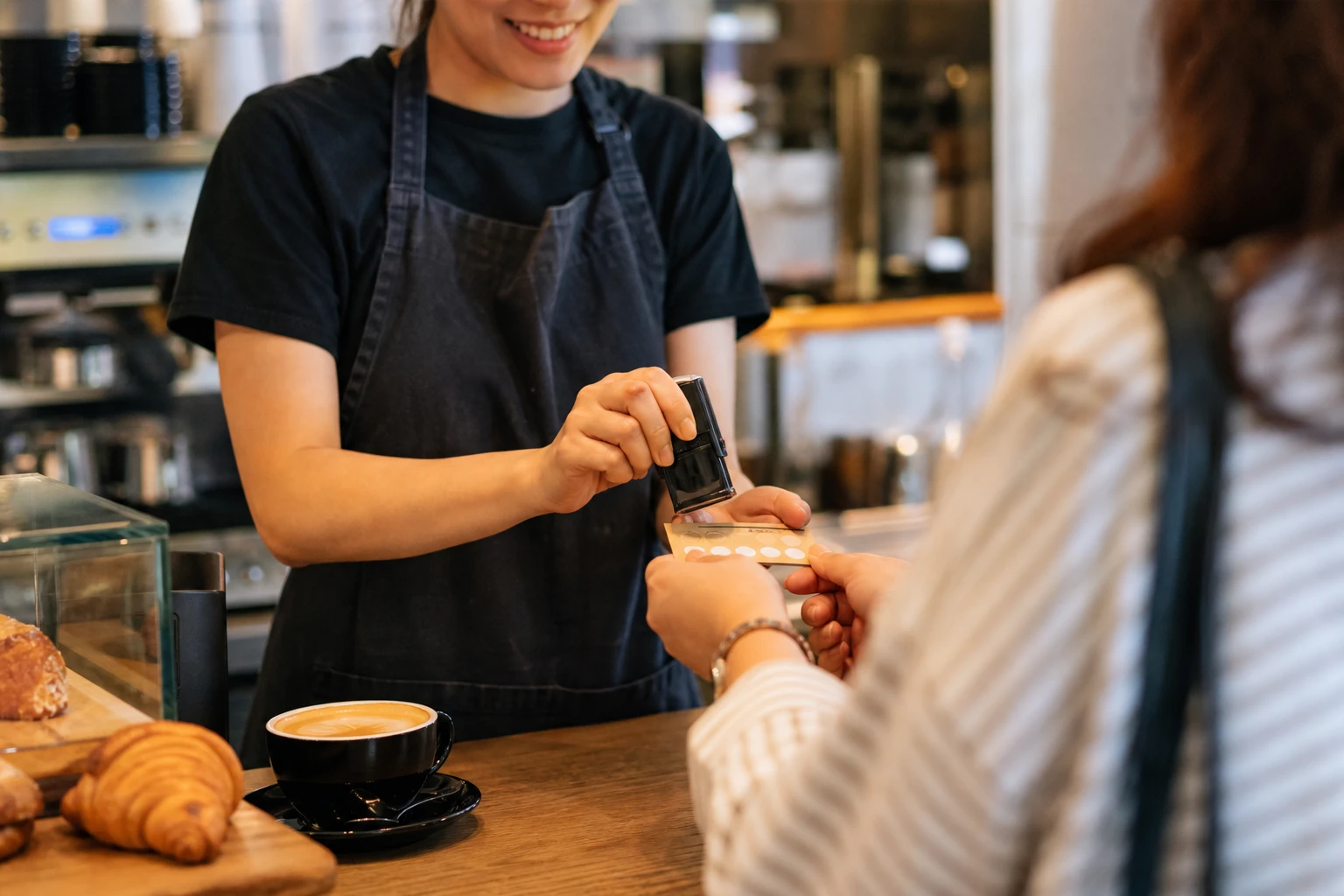 Barista stamping a paper loyalty card for a returning customer