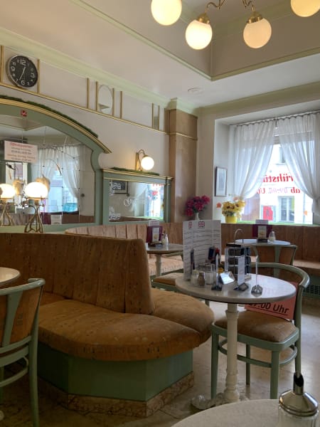 Inside of quaint vintage 60/70s Viennese cafe Gumpendorf Cafe Condetorei with beiege upholstered seating and green accents