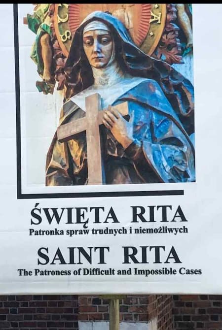 Sign that shows an image of Saint Rita with the Polish text ŚWIĘTA RITA Patronka spraw trudnych i niemożliwych and in English SAINT RITA The Patroness of Difficult and Impossible Cases