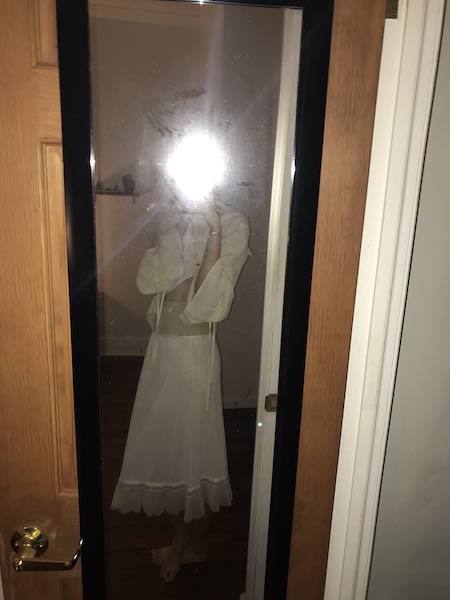 Mirror selfie with flash obscuring face posed a breath before sideways. Barefoot and wearing white slip skirt, nude girdle shorts pulled high, poets blouse pulled up at front.