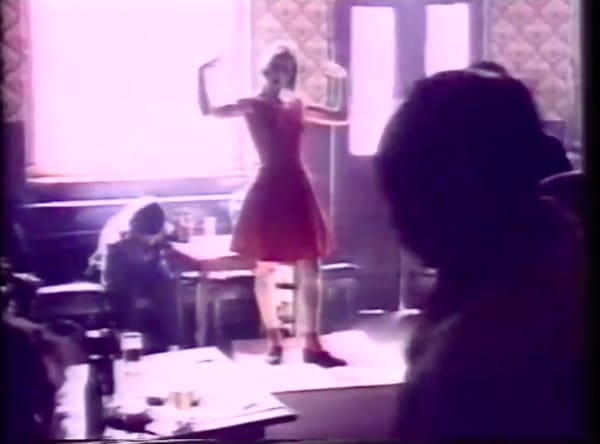 blonde in a red dress posing in a room as if dancing
