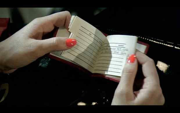 János Xantus - Eszkimo asszony fazik (1984), Hands with orange nail polish looking through small address book