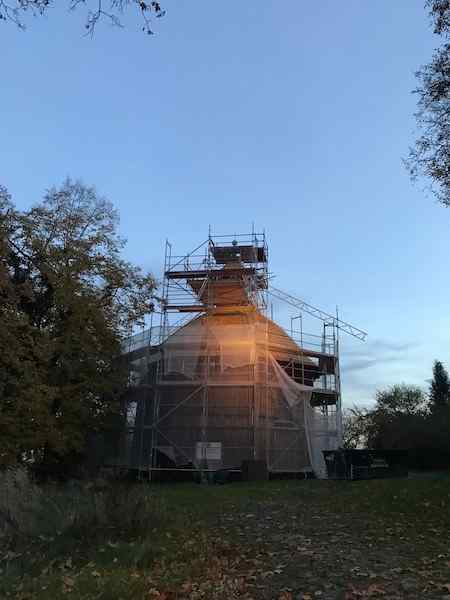 Old 8 sided nunnery or church under construction wood lit up beautifully by construction lights under scaffolding