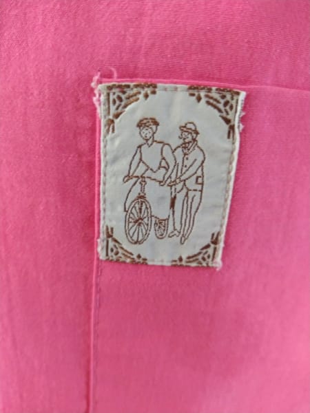 tag/patch on vinted top showing a man helping or teaching a woman go biking