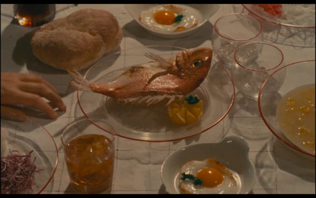 Agnes Varda - 7p., cuis., s. de b., … à saisir (1984), dinner table with various items, including a prominent fish