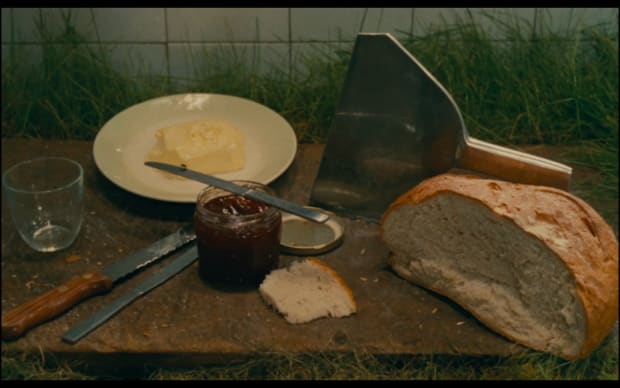 Agnes Varda - 7p., cuis., s. de b., … à saisir (1984), bread and butter and jam on a cutting board on a table covered in grass