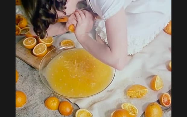 Věra Chytilová - Fruit of Paradise (1970), a girl squeezing oranges into a large bowl of juice surrounded by orange halves