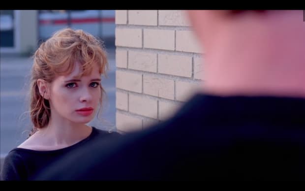 Hal Hartley - The Unbelievable Truth (1989), looking over the s houlder of someone whose back it turns to us we see a stunning blonde looking desperate and forlorn and passionate and hot